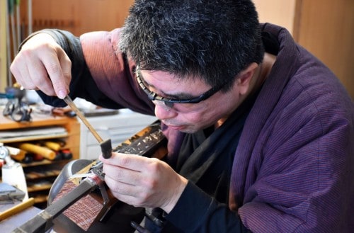 A skilled engraver at Bizen Osafune sword museum working on a blade