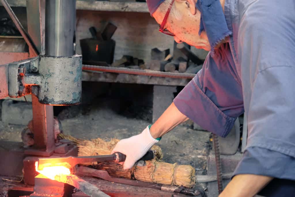 Traditional Japanese sword maker in Kumamoto hammering red iron 