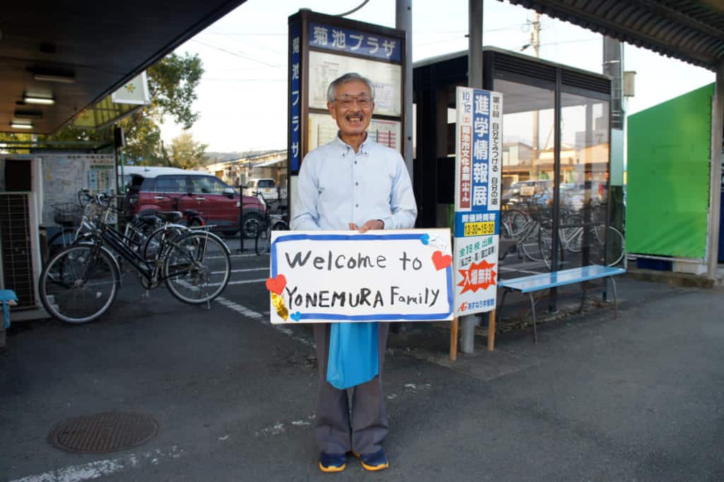 Mr Yonemura, holding a sign written "Welcome to Yonemura family"