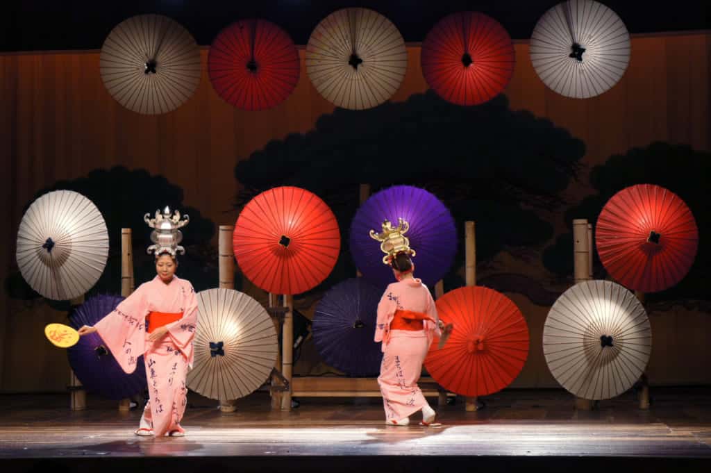 Two dancers, performing Yamaga lantern dance in front of paper umbrellas