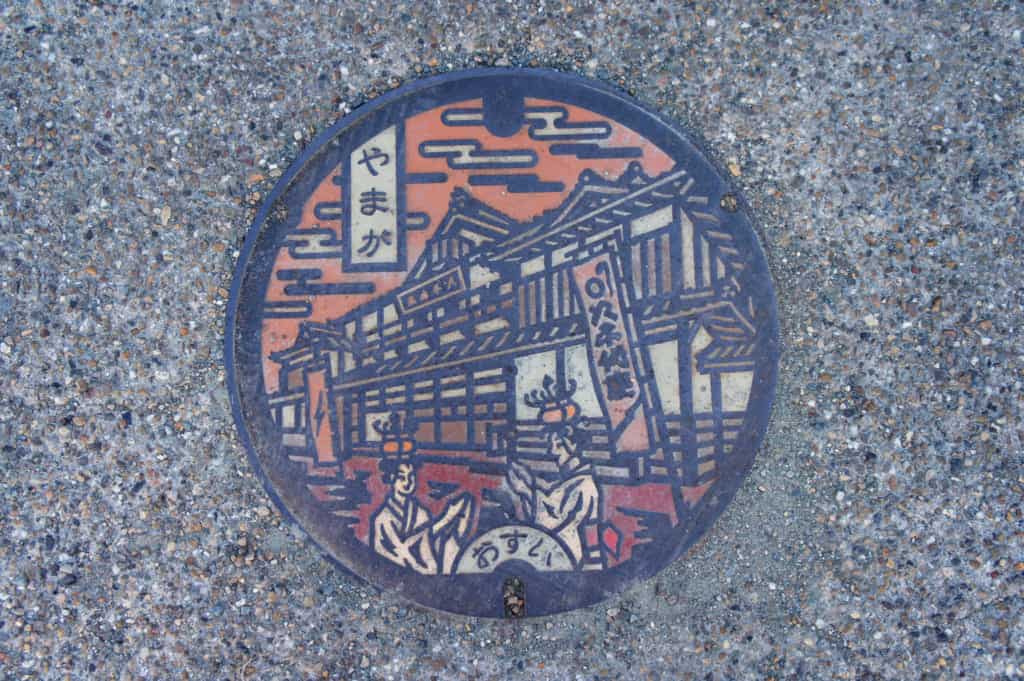 A manhole in Yamaga showing the Yachiyoza theatre and dancers wearing lanterns on their head
