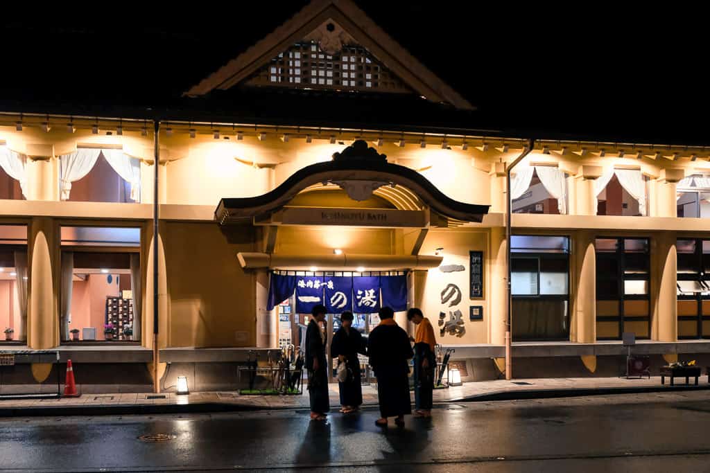 men wearing yukata in front of a bathhouse in Kinosaki Onsen, Japan