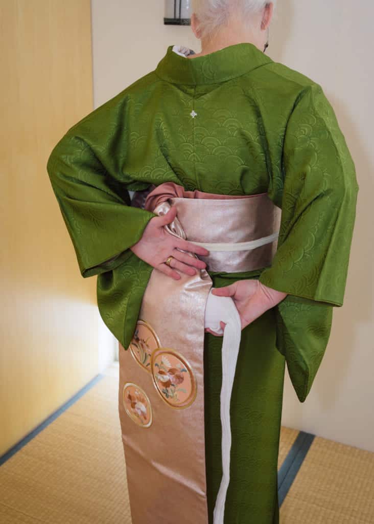 slip the obi-makura under the wide end of the obi and grab the tie with your other hand