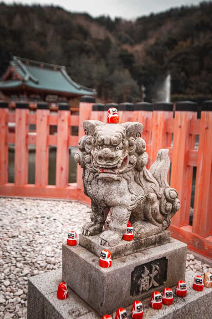 many daruma over a stone statue in Katsuo ji temple