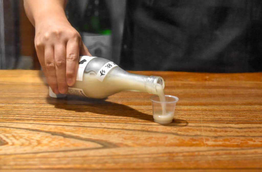 man pours sake into cup for customer on Sado Island in Niigata