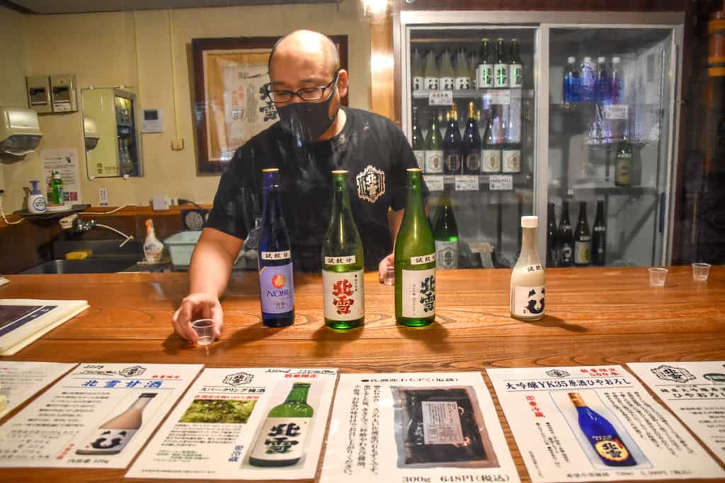 masked man serves sake on Sado Island in Niigata