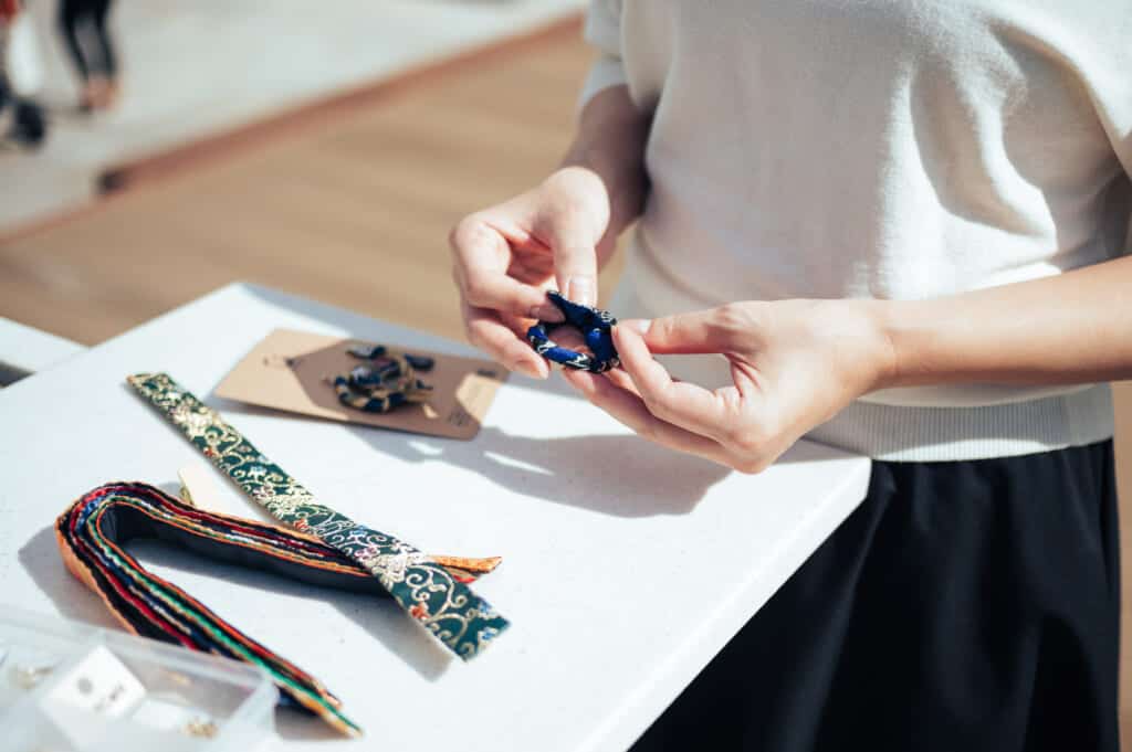 woman assembles earrings from recycled obi