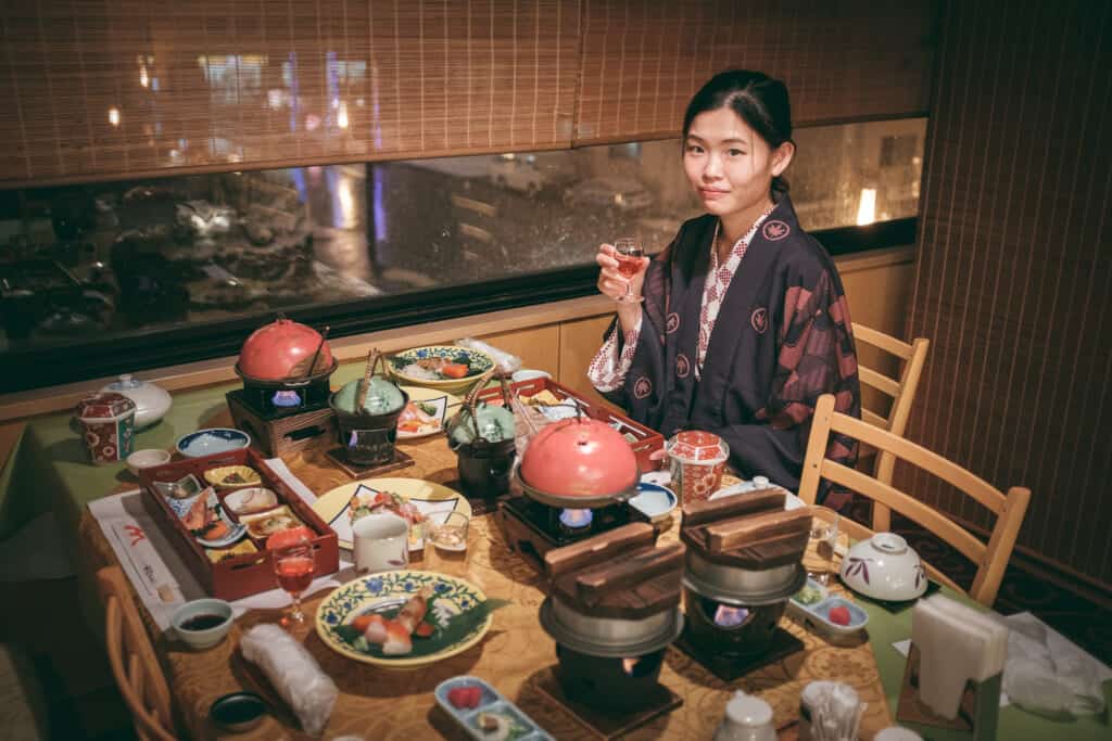 woman seated at an elaborate dinner spread in a ryokan