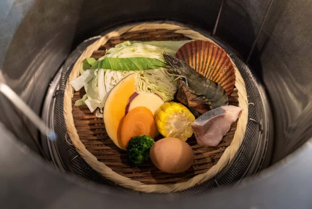 vegetables and seafood placed in steam of onsen hot spring in Beppu, Oita