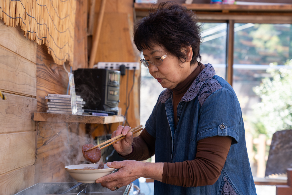 Mrs. Ogura prepares food in the kitchen
