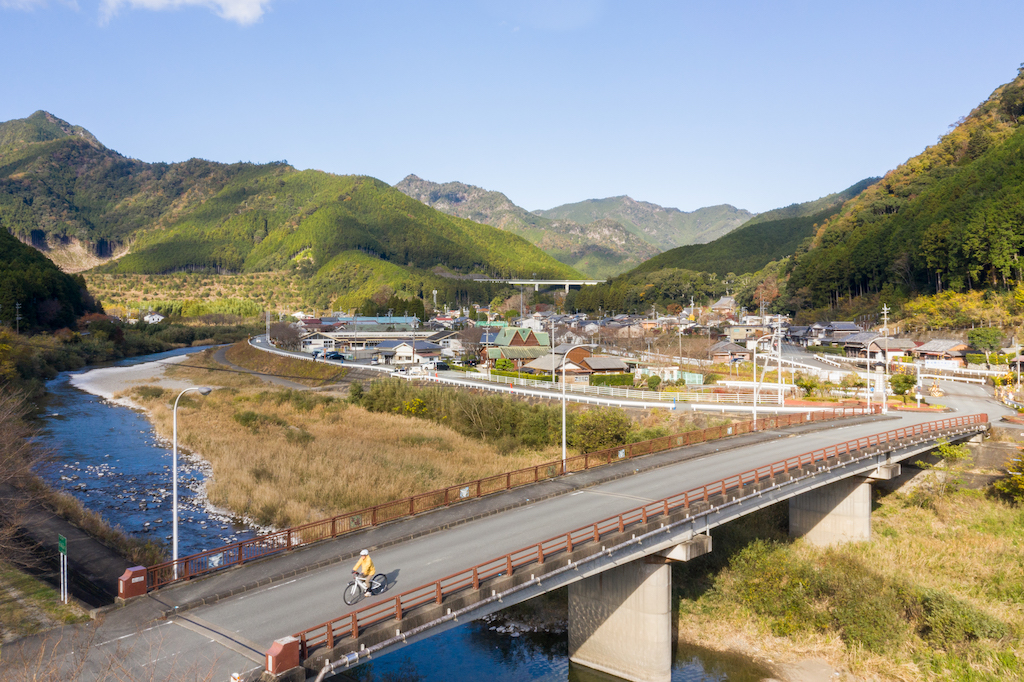 Cycling across a bridge over a river in the mountains of Kumano Kodo