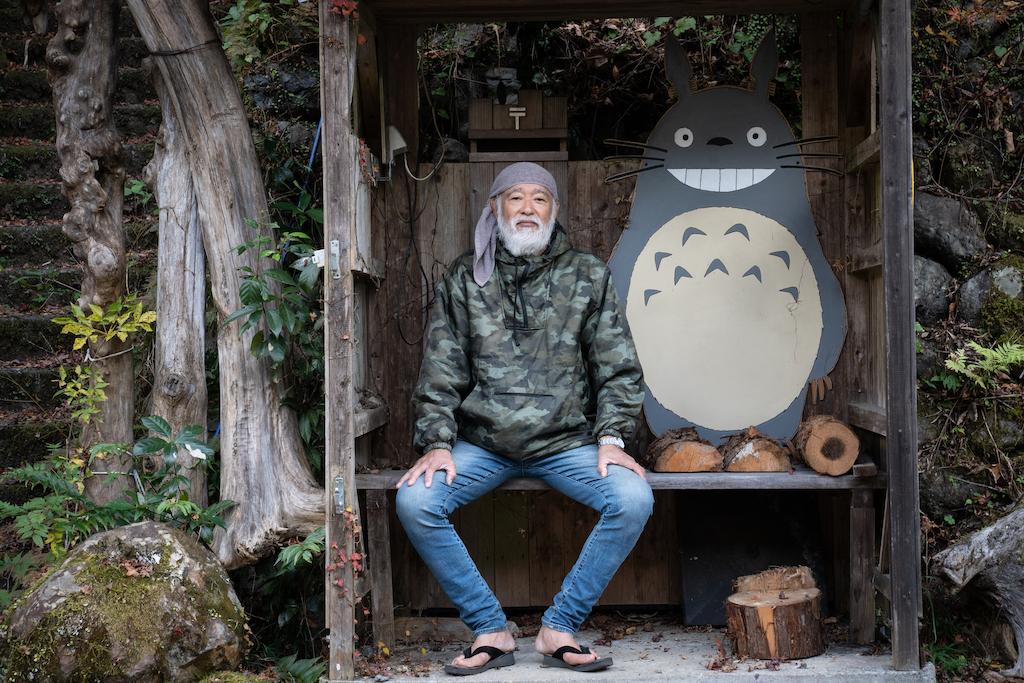 Mountain hermit sitting on bench next to Totoro
