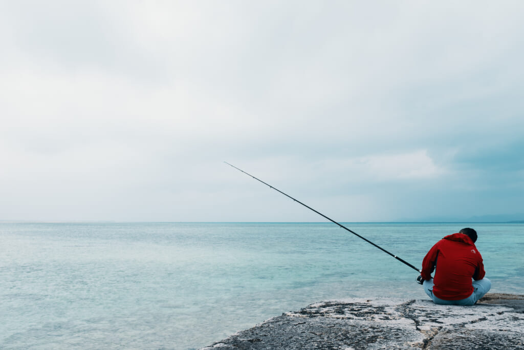 a fisherman waiting for his first catch of the year in taketomi island