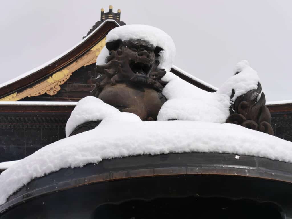 stone lions covered in snow at zenkoji temple