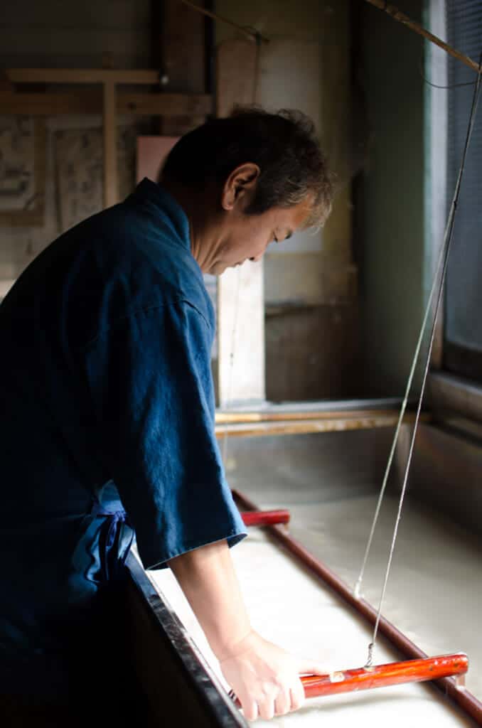 Japanese artisan making washi paper in his workshop