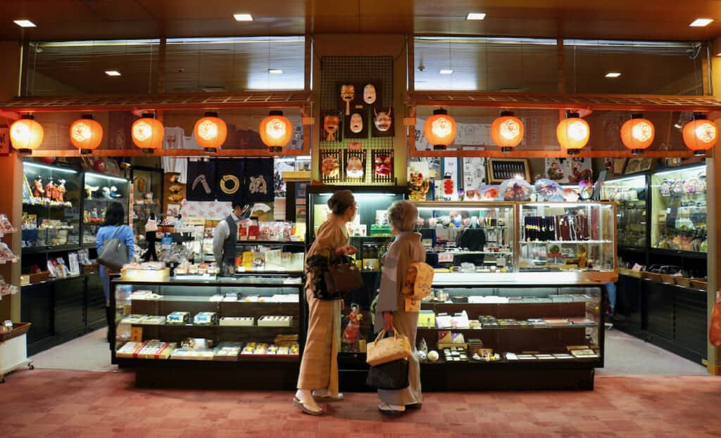 Two women wearing kimono in front of National Theatre shop