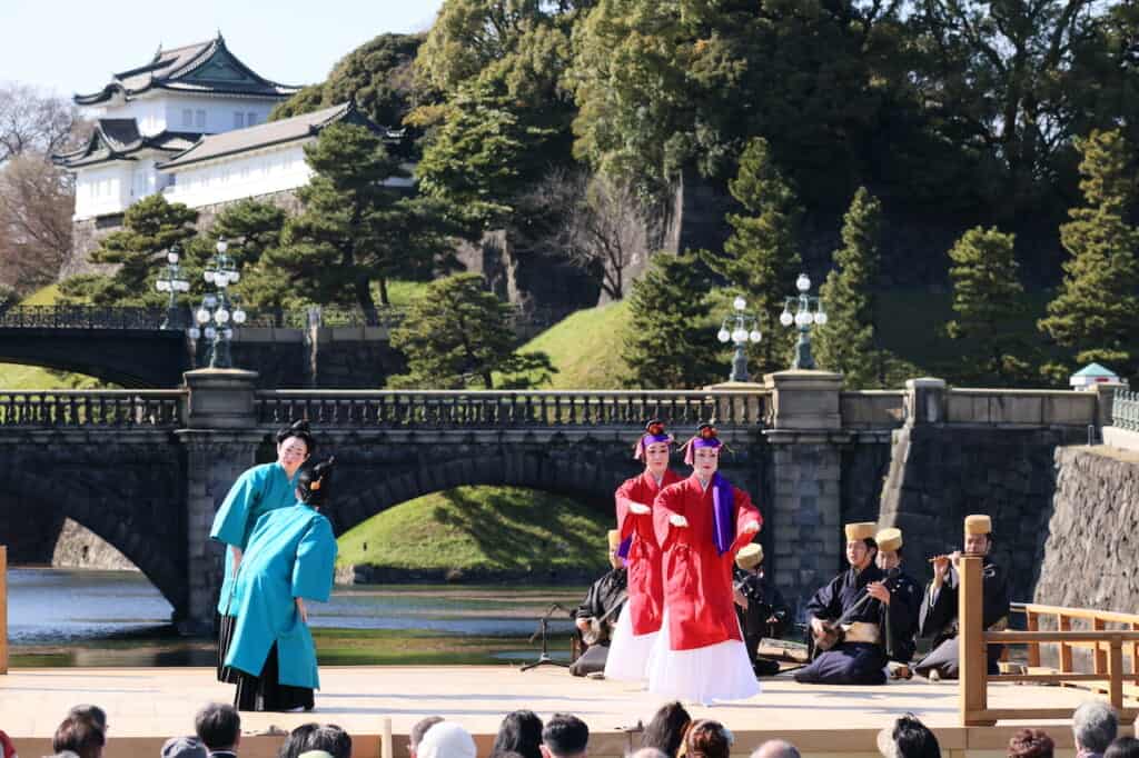 traditional Japanese dance, 2 dancers in red, 2 dancers in blue on stage in front of Imperial Palace in Japan