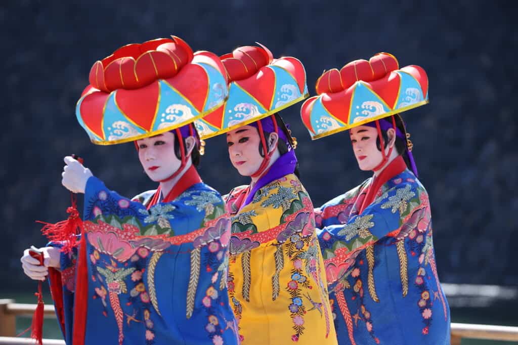 3 traditional Okinawa dancers wearing bright hats in Japan