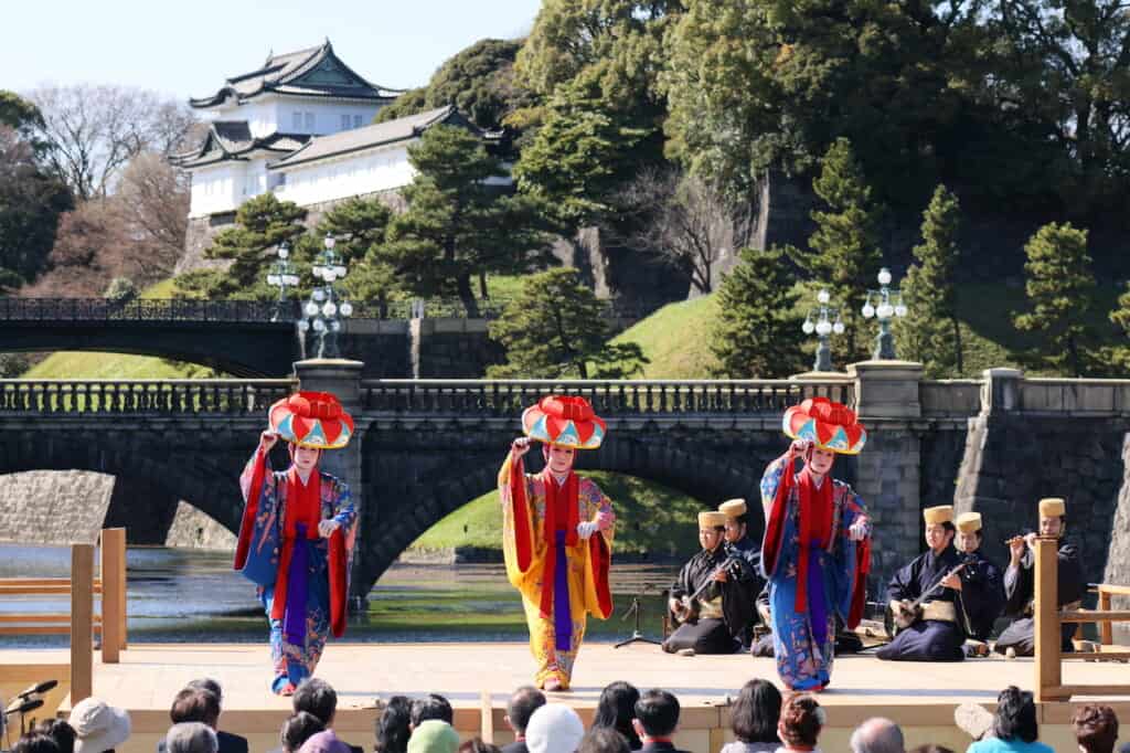 3 traditional Okinawa dancers in front of Double Bridge and Imperial Palace in Japan