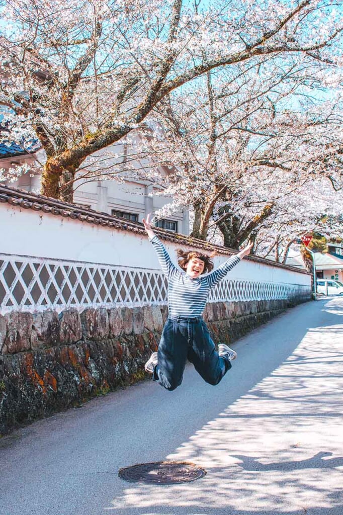 woman jumping in front of cherry blossoms in Japan