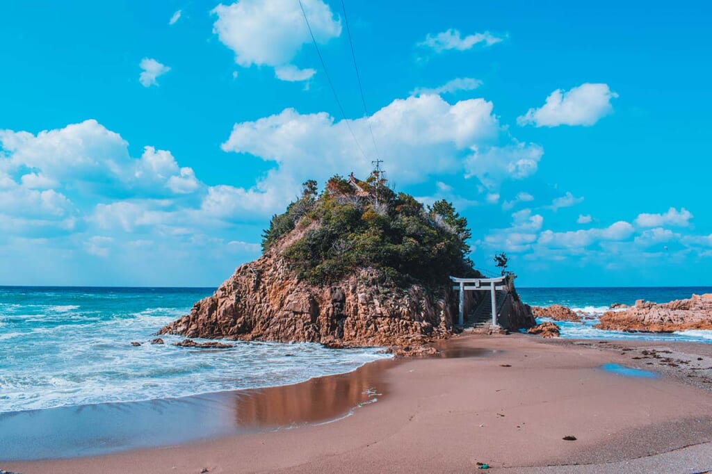 A tiny Japanese island off the coast with a shrine in front of it in Japan