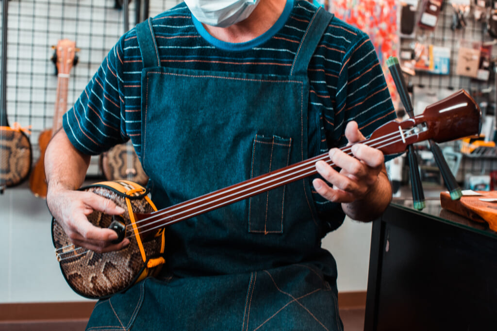 A Japanese man playing a traditional japanese instrument in Okinawa