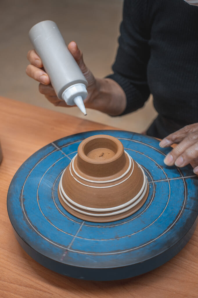 a woman painting a ceramic bowl in Okinawa, Japan