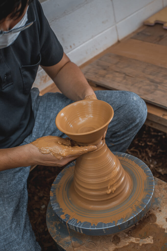 a man using a pottery wheel to make a vase in okinawa, Japan