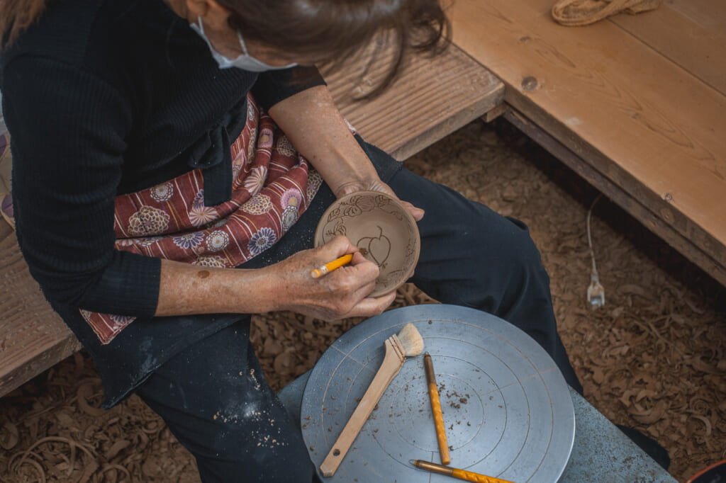 a woman carving a bowl in Okinawa, Japan