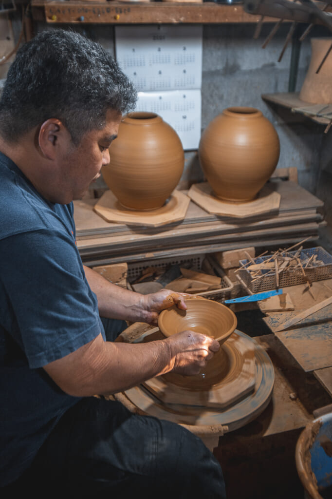 Nakama-san shaping a ceramic plate in the potter's wheel in Okinawa, Japan