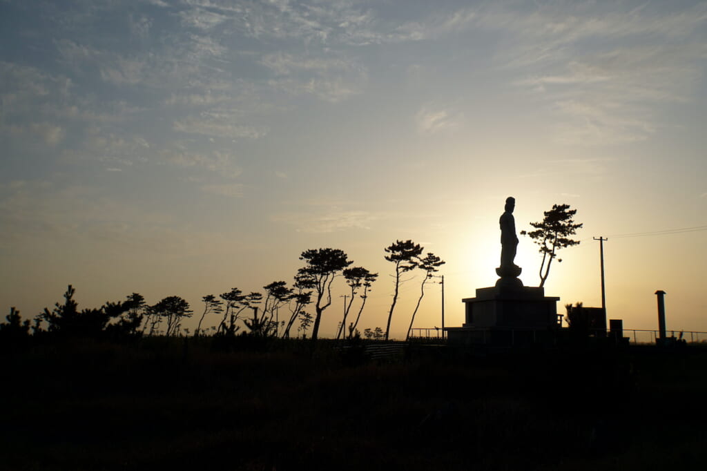 silhouette of Buddha statue and trees at dusk in Japan