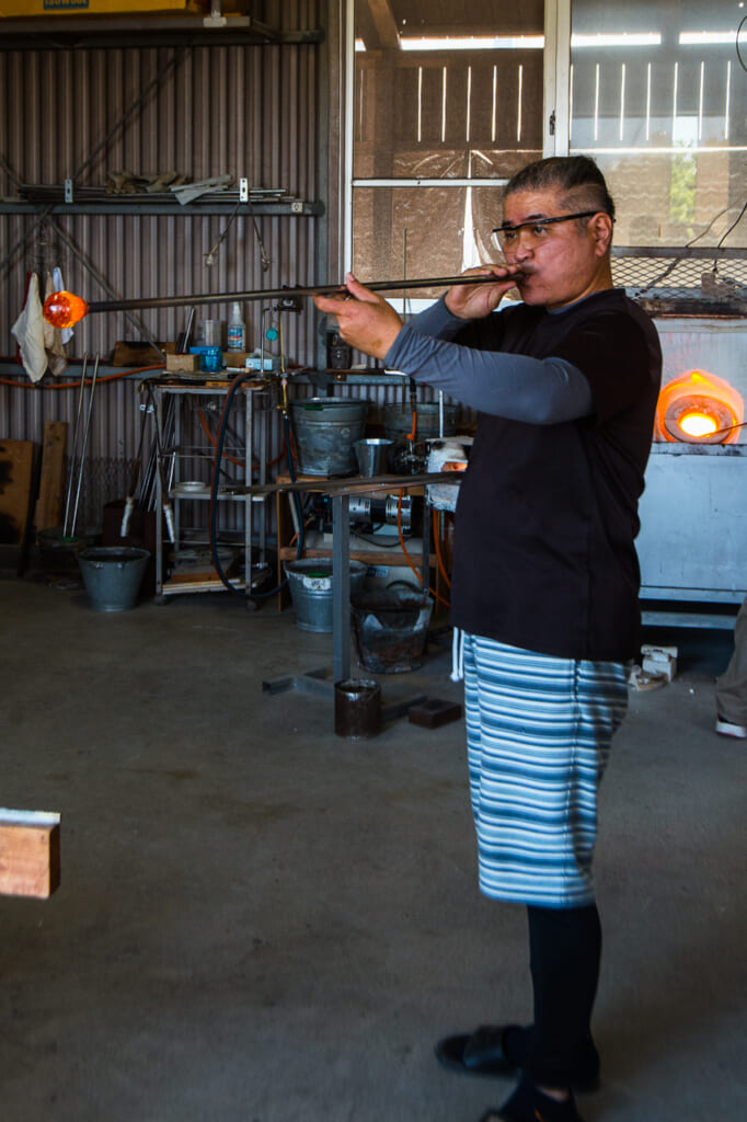 Japanese craftsman, Kaneshi blowing a glass in Okinawa, Japan