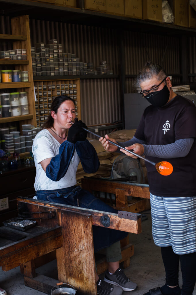 woman blowing a glass in a Japanese glass blowing workshop and studio in Japan
