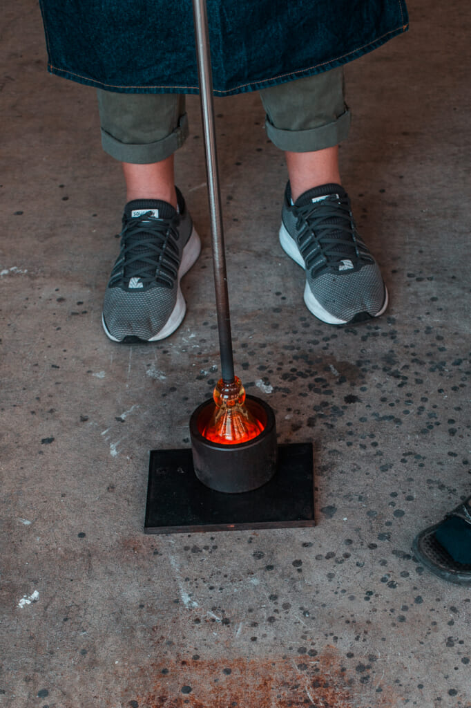 woman putting a glass inside a mold in a Japanese glass blowing workshop and studio in  Japan