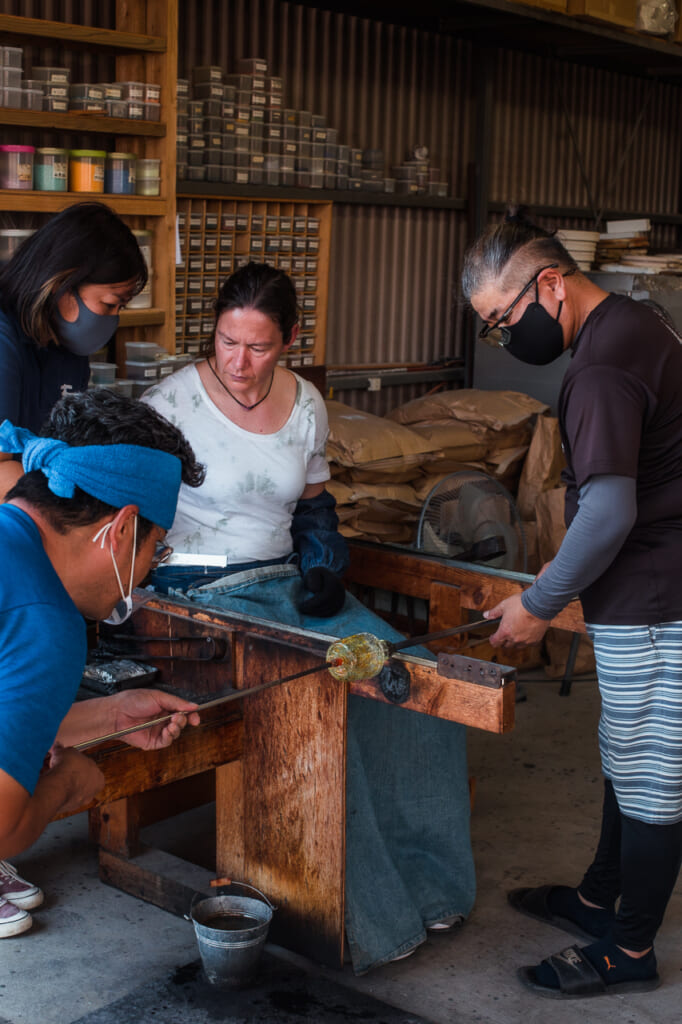 woman shaping a glass in a Japanese glass blowing workshop and studio in Okinawa, Japan