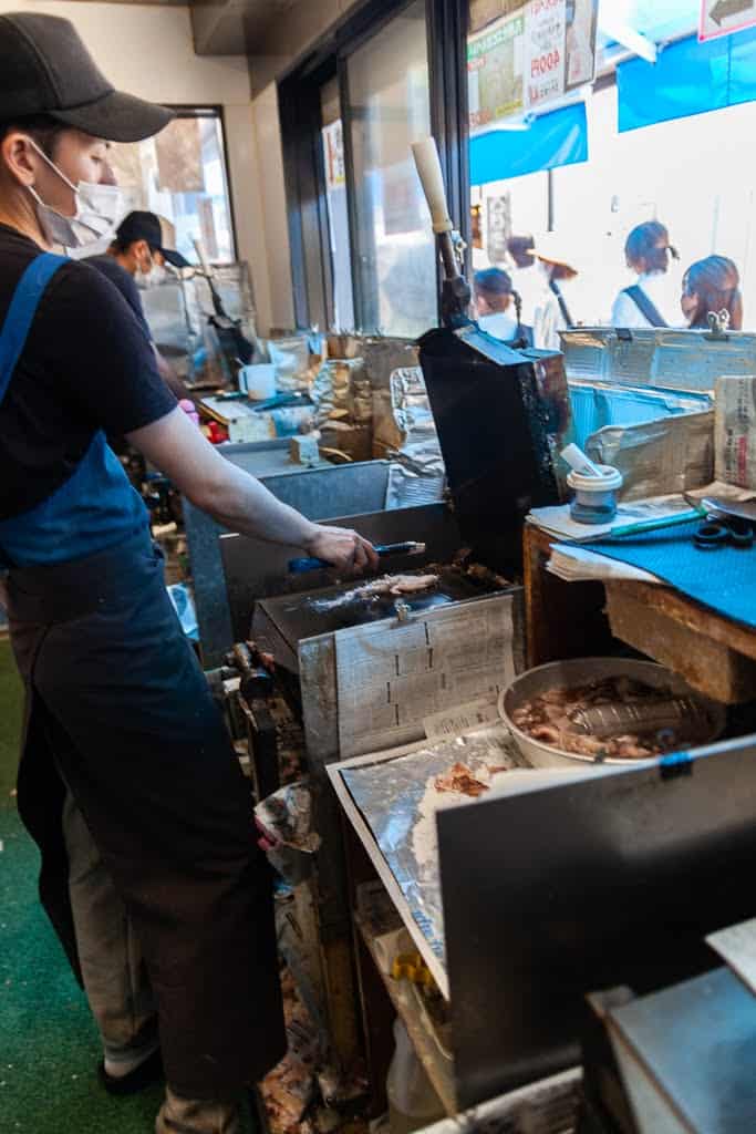 man preparing shrimp on an iron grill in Japan