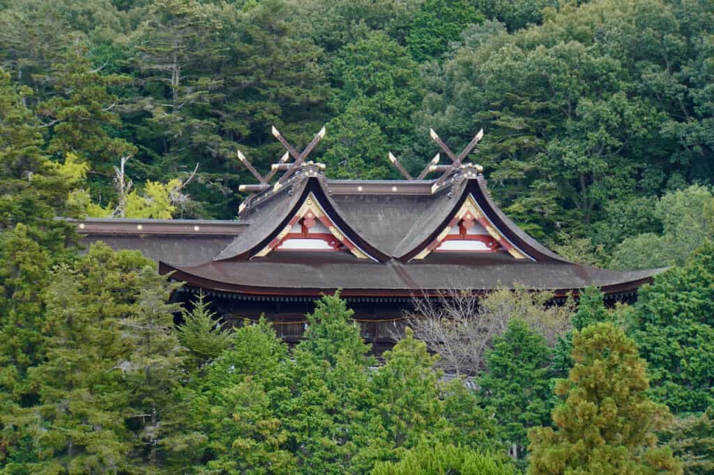 gabled roof of Kibitsu Shrine nestled in forest in Japan