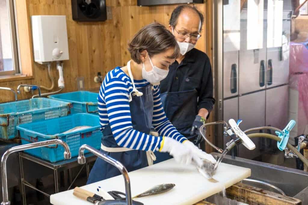Girl filleting fish caught in Japanese waters near Amanohashidate
