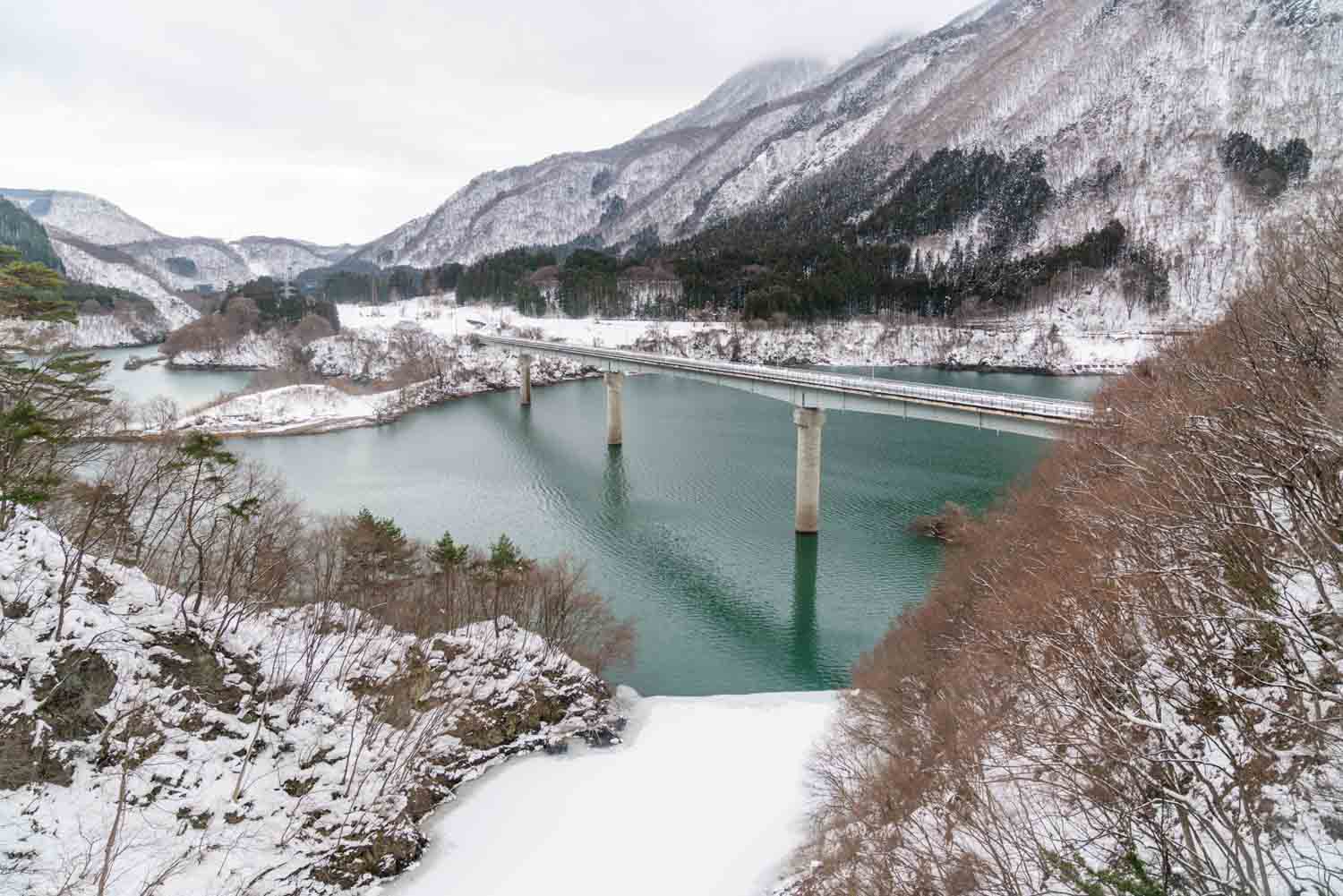 snowy view of bridge and mountains from Ozatorotembo Train