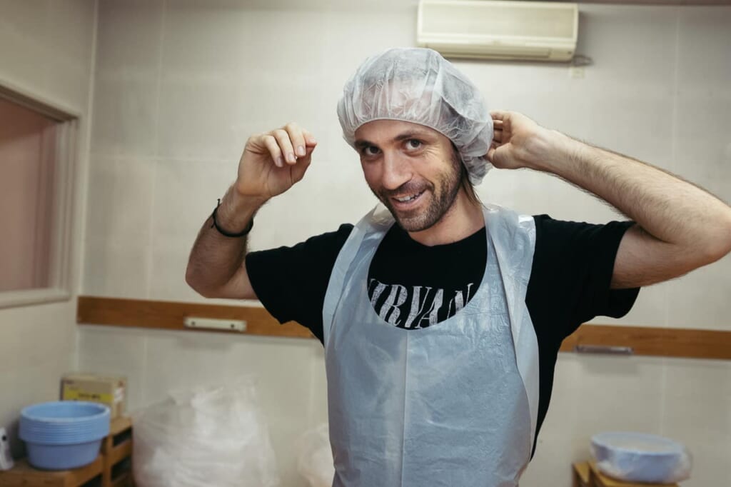 man wearing hairnet, preparing to make udon by hand in japan