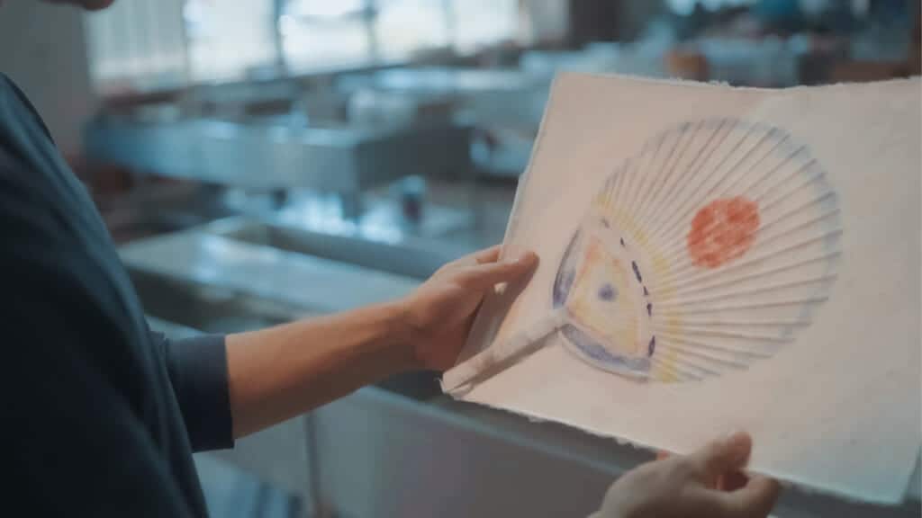 person holding Japanese washi paper which is showing a hand fan