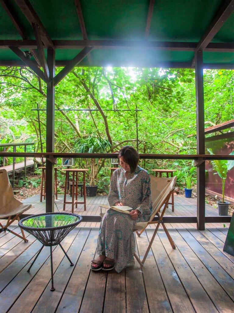woman sitting in chair on outdoor balcony reading a book in Hoshino Resort, Okinawa