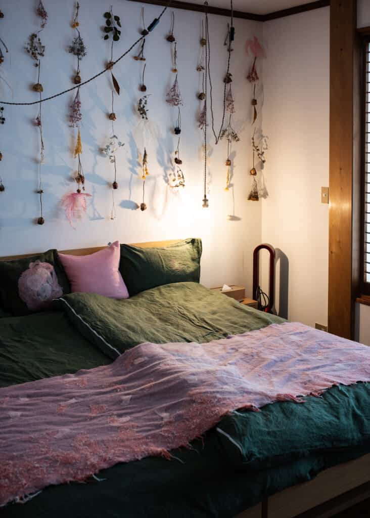 homey bedding with pink pillows and decorative art handings on the white wall