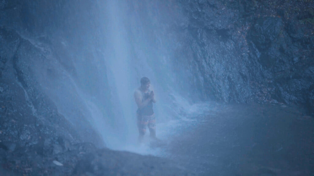 person standing under a waterfall