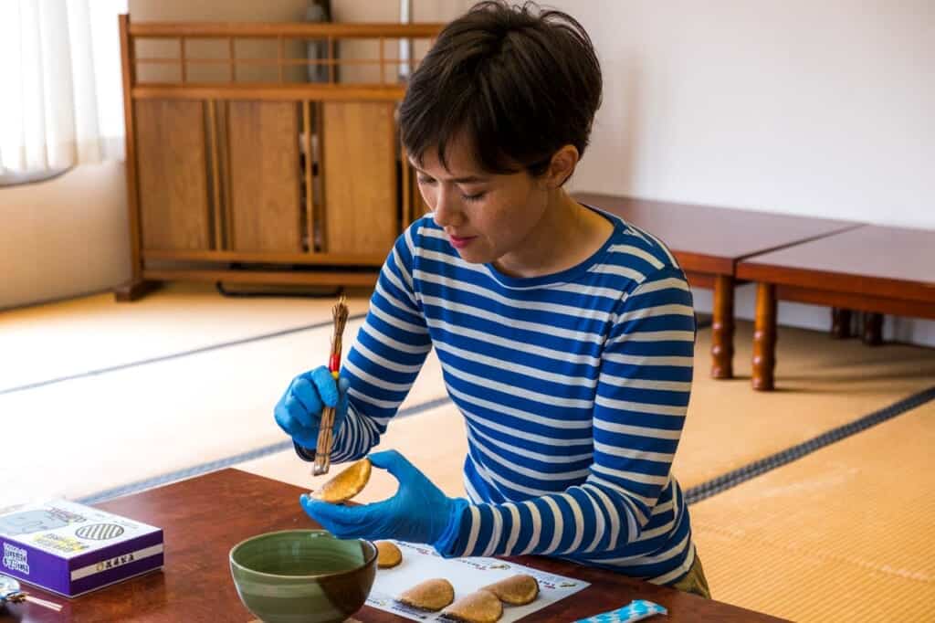 woman swiping syrup onto cracker in japanese workshop
