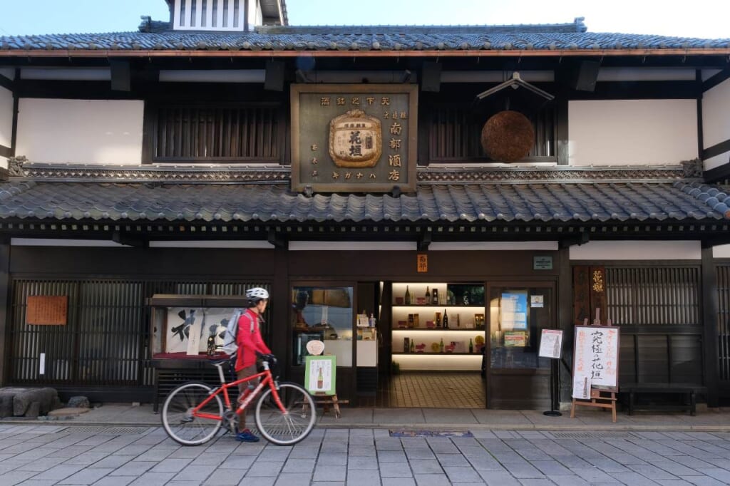 Bicycle rider infron of an old traditional Japanese house