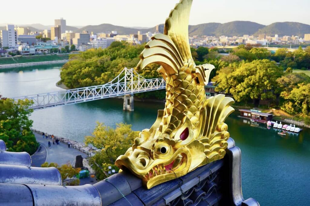 Okayama Castle shachihoko over backdrop of Tsukimi Bridge and river