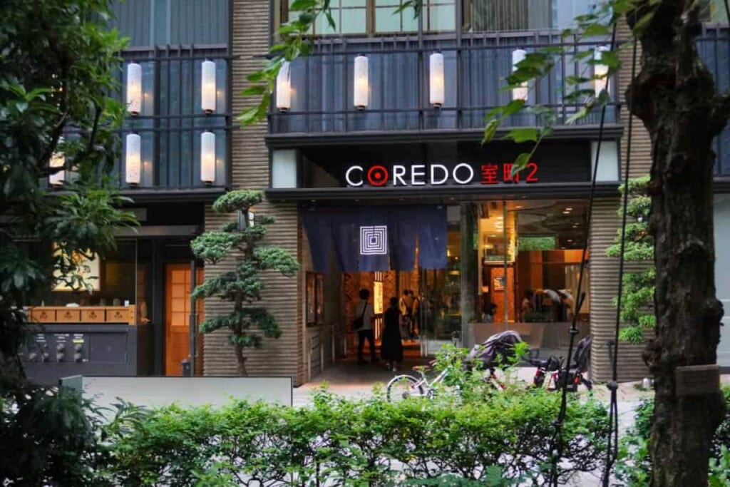A Coredo mall entrance surrounded by sparse greenery in Tokyo