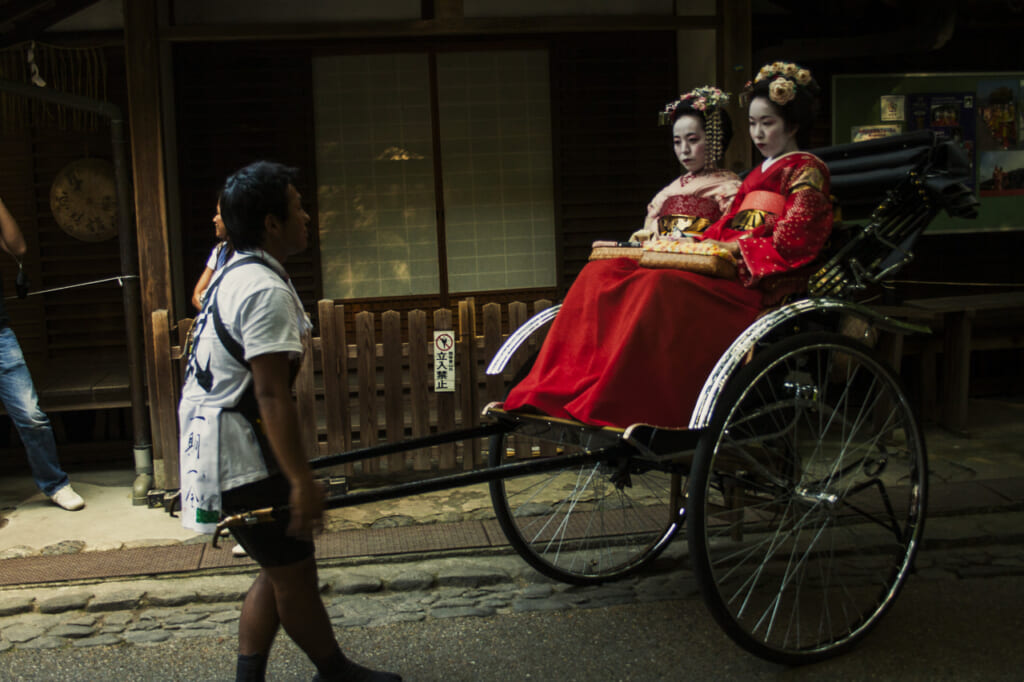 Tourists in Geisha make-up riding a rickshaw in Gion