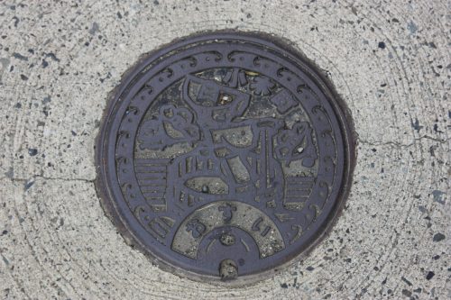 Bouche d'égout représentant une conductrice de tarai-bune sur l'île de Sado, dans la Préfecture de Niigata, Japon